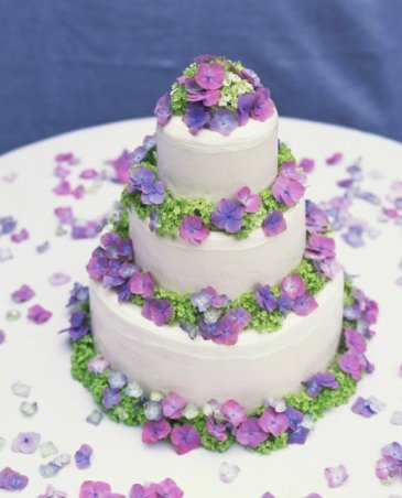Torta a piani decorata con fiori e piccoli decori di zucchero